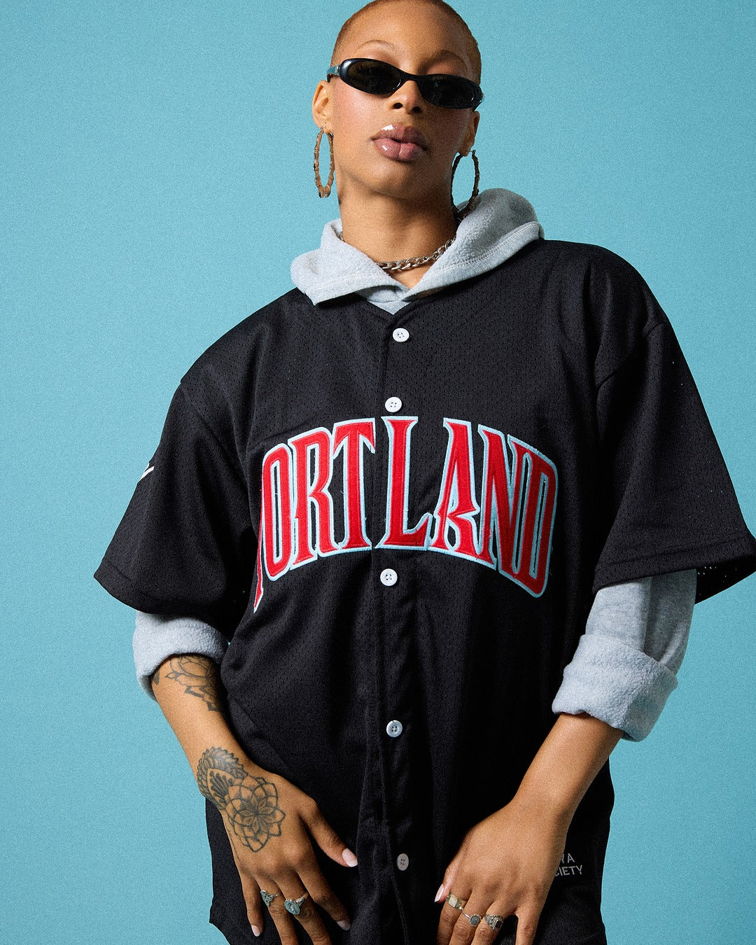 Person wearing a black 'Portland' baseball jersey against a blue background
